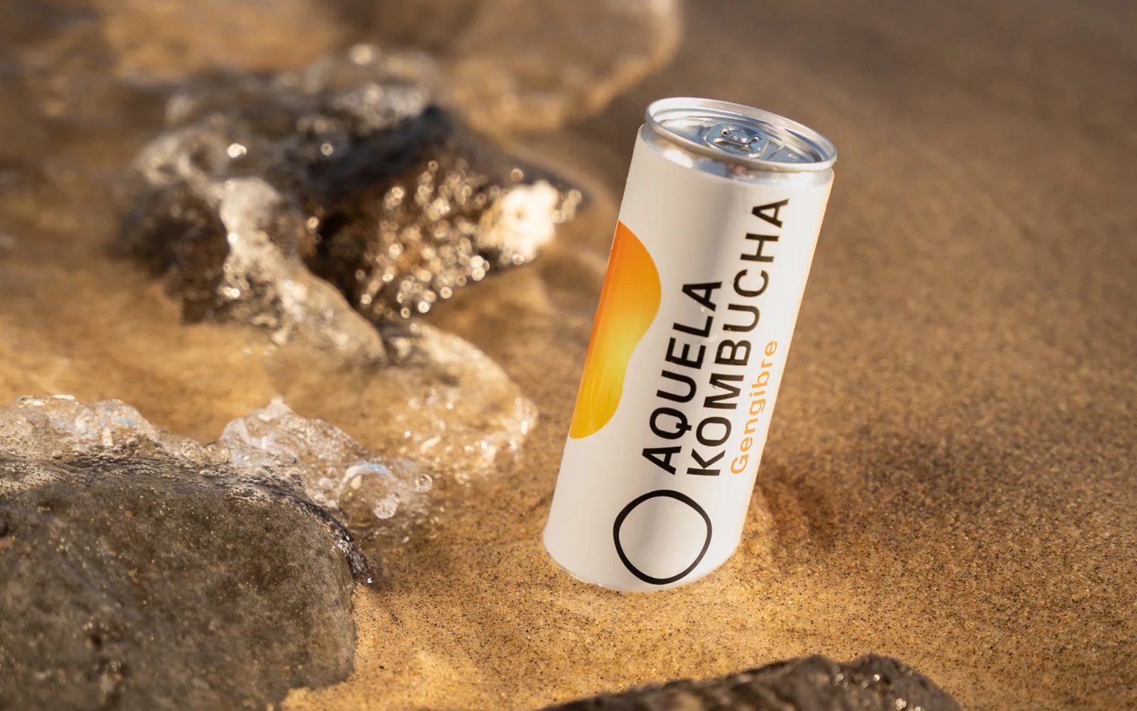 Lata Aquela Kombucha Gengibre de 25 cl na areia junto à água